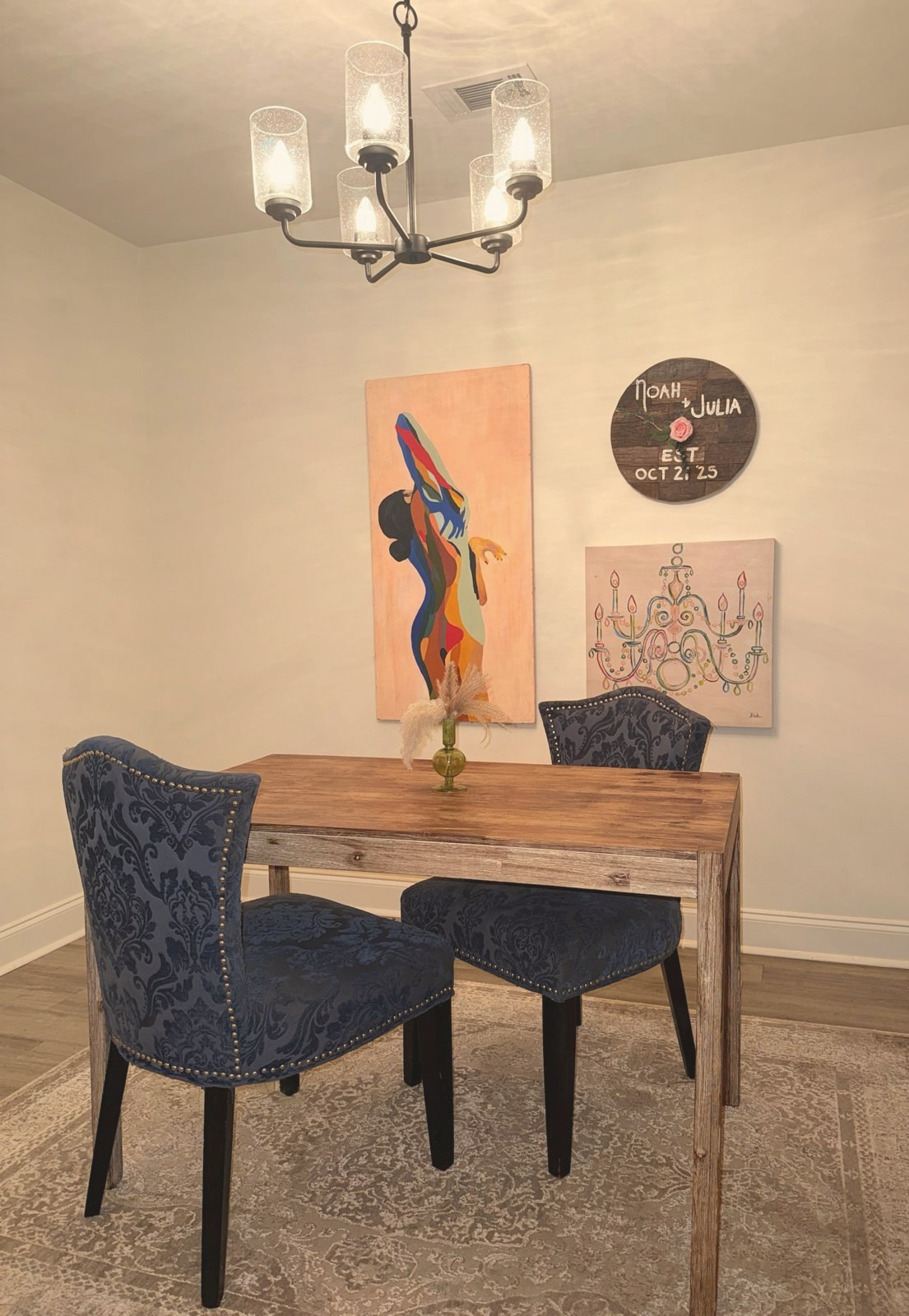 Dining nook with blue velvet chairs, a wood table, and a Noah and Julia sign