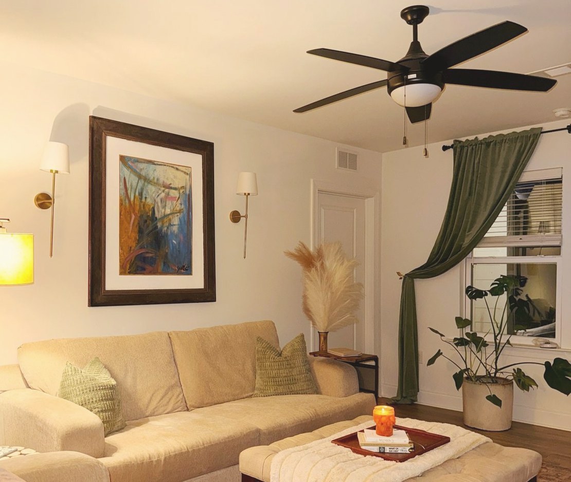 Julia's living room with a cream sofa, sage pillows, green curtains, and a large painting
