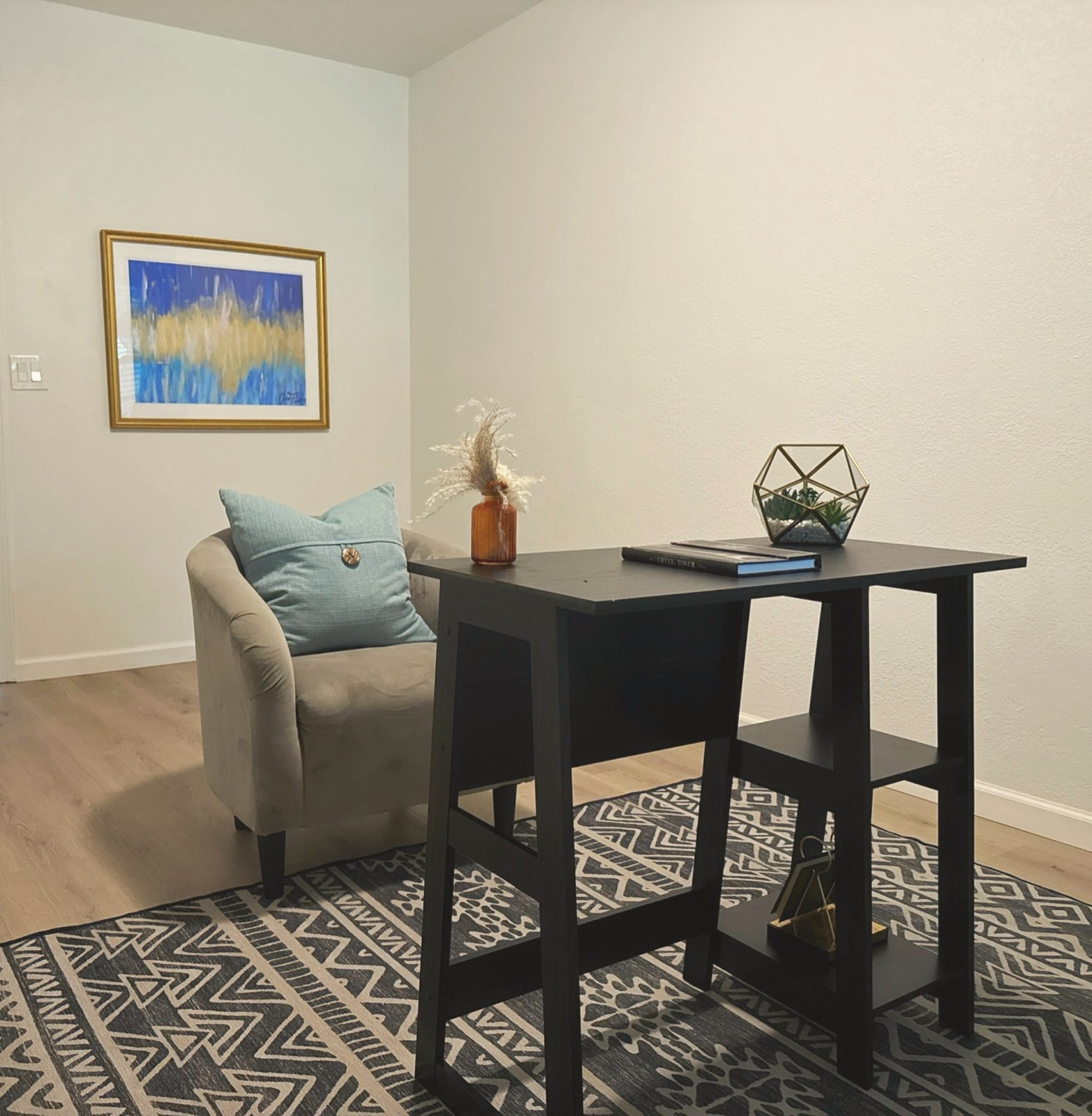 Home office with a black desk, gray chair, and blue abstract art